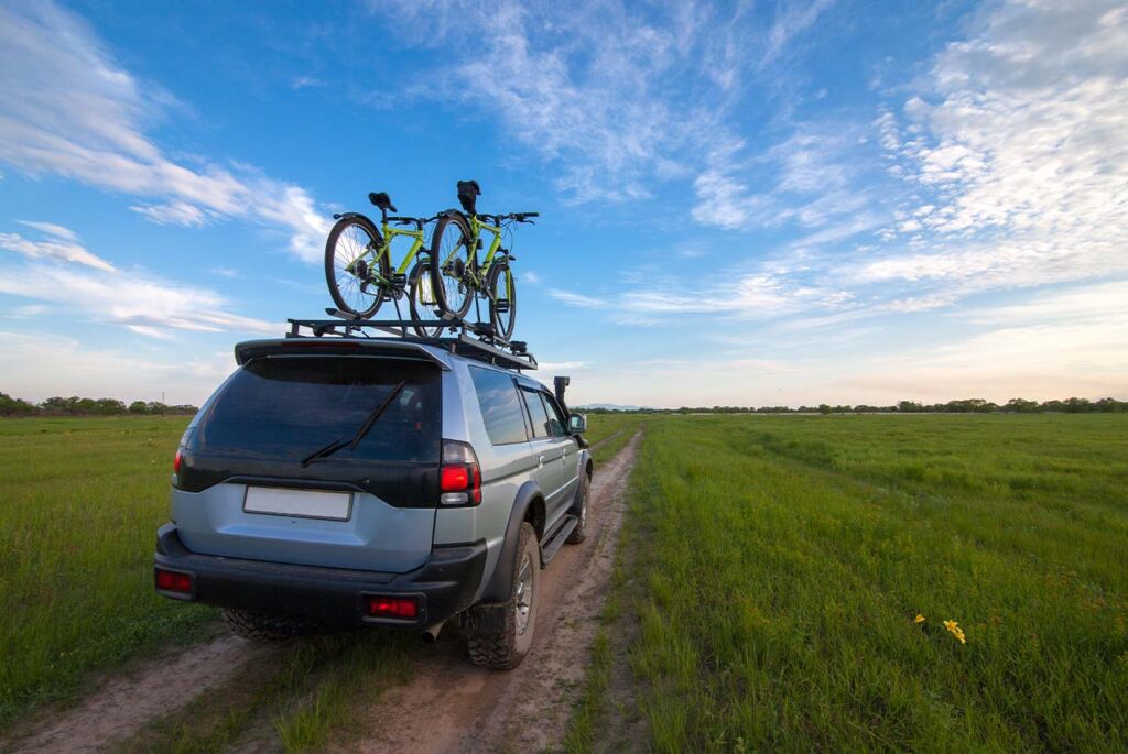 Mitsubishi Pajero z bagażnikiem dachowym jedzie po polnej drodze
